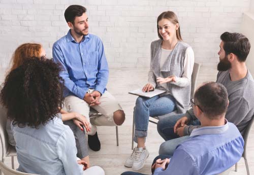 A group of people sitting in a circle, talking to one another.